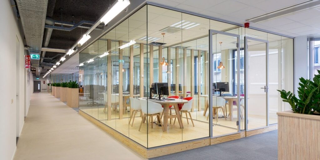 Moderne glazen kantoorruimte met vergaderplek en plantenbakken.