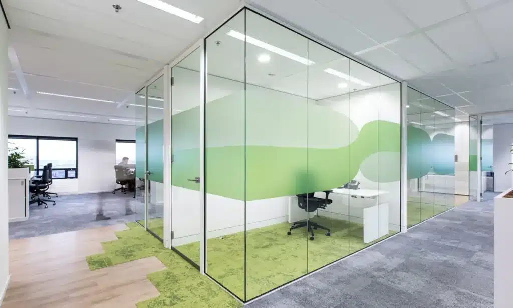 Moderne kantoorruimte met glazen wanden en groene decoratie.