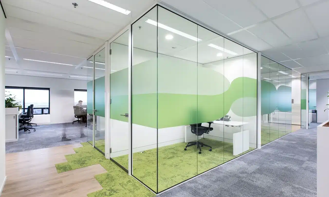Moderne kantoorruimte met glazen wanden en groene decoratie.