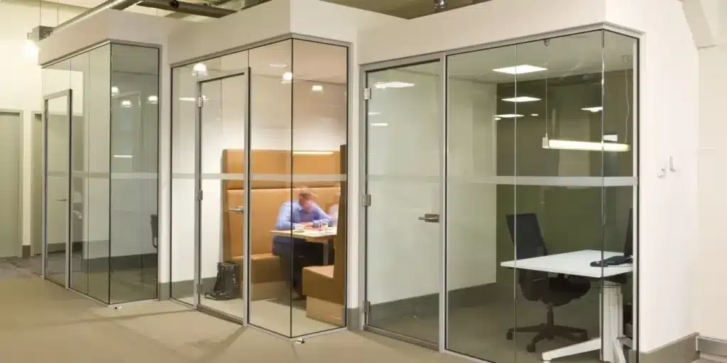 Glazen vergaderruimtes in een kantooromgeving, werknemer aan het werk.