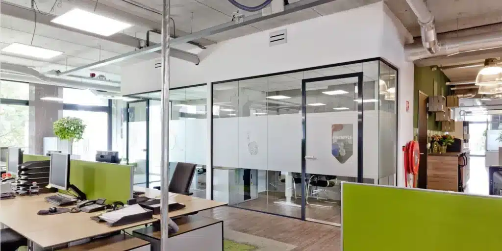 Modern kantoor met glazen vergaderruimte en bureaus.