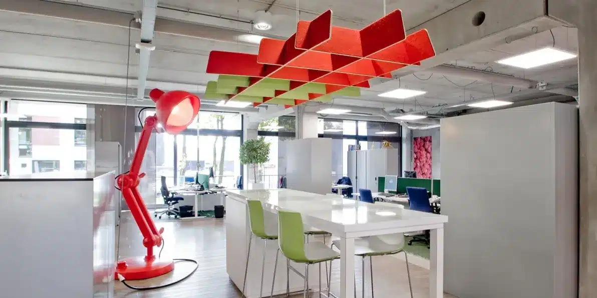 Modern kantoorinterieur met rode lamp en akoestische panelen.