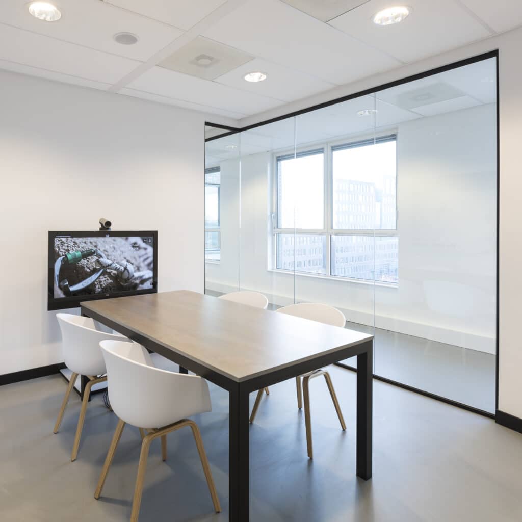 Moderne vergaderruimte met tafel, stoelen en glazen wand.
