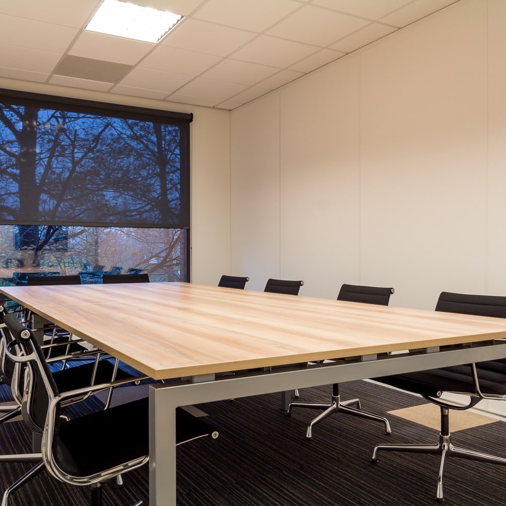 Vergaderruimte met een grote houten tafel en zwarte stoelen